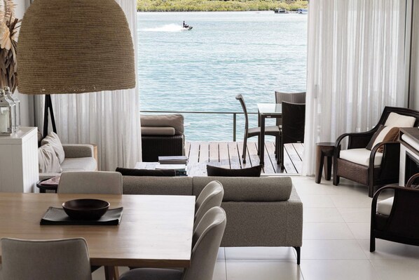 Una sala de estar moderna con vista al mar, que incluye un sofá, una mesa de comedor y sillas.