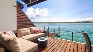 Een terras met een bank en een ronde tafel, met uitzicht op een wateroppervlak.
