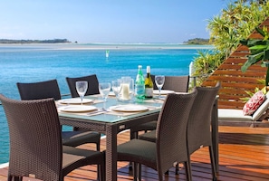 Mesa de comedor para seis personas con sillas, vista al mar y terraza de madera.