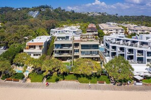 A coastal residential area with modern buildings, a beach, and lush greenery.