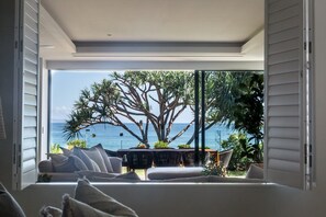 Une pièce dotée d’une grande fenêtre donnant sur un arbre et la mer.