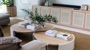 A modern living room with a sofa, two coffee tables, and a bookshelf.