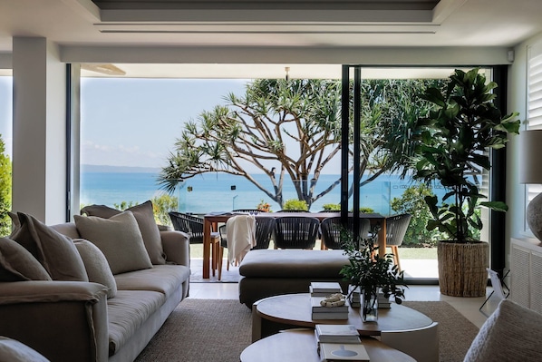 A modern living room with a sofa, coffee table, and a view of the sea.