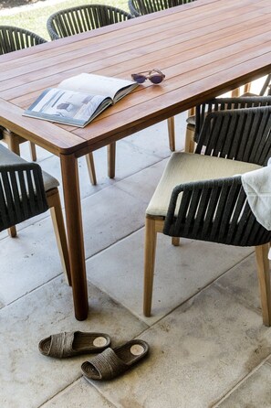 A wooden table with a magazine and sunglasses on it, surrounded by chairs.