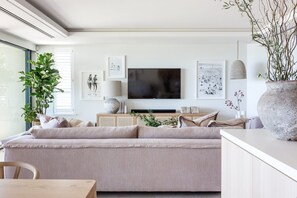 Ein modernes Wohnzimmer mit einer Couch, einem Flachbildfernseher und Kunstwerken an der Wand.