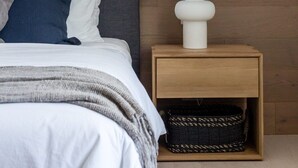 A bedroom with a bed, a nightstand with a lamp, and two framed pictures on the wall.