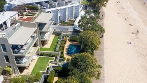 Un hotel moderno con piscina en la azotea, ubicación frente a la playa y un jardín bien cuidado.
