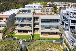 Ein modernes, mehrgeschossiges Wohngebäude mit Balkonen, einer Dachterrasse und einem gepflegten Garten.