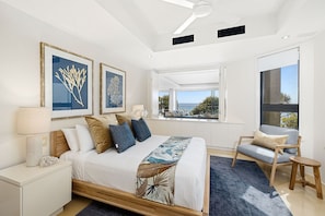 Relax in a serene space with a large bed, nightstands, and a ceiling fan, offering a peaceful view of the outdoors.