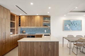 Eine moderne Küche mit Holzschränken, einer gefliesten Spritzschutzwand und einem Essbereich mit Tisch und Stühlen.