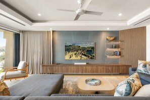 A modern living room with a large painting, a ceiling fan, and a seating area with a coffee table.