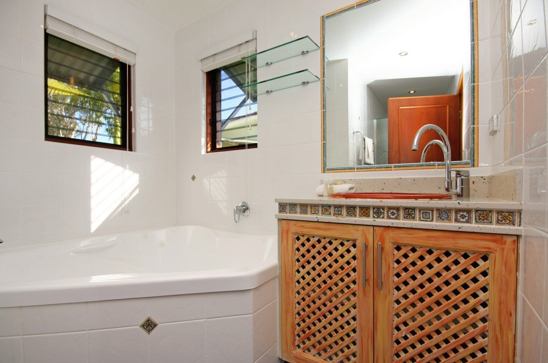 Un baño con bañera, un lavabo con espejo y una ventana con vistas a árboles.