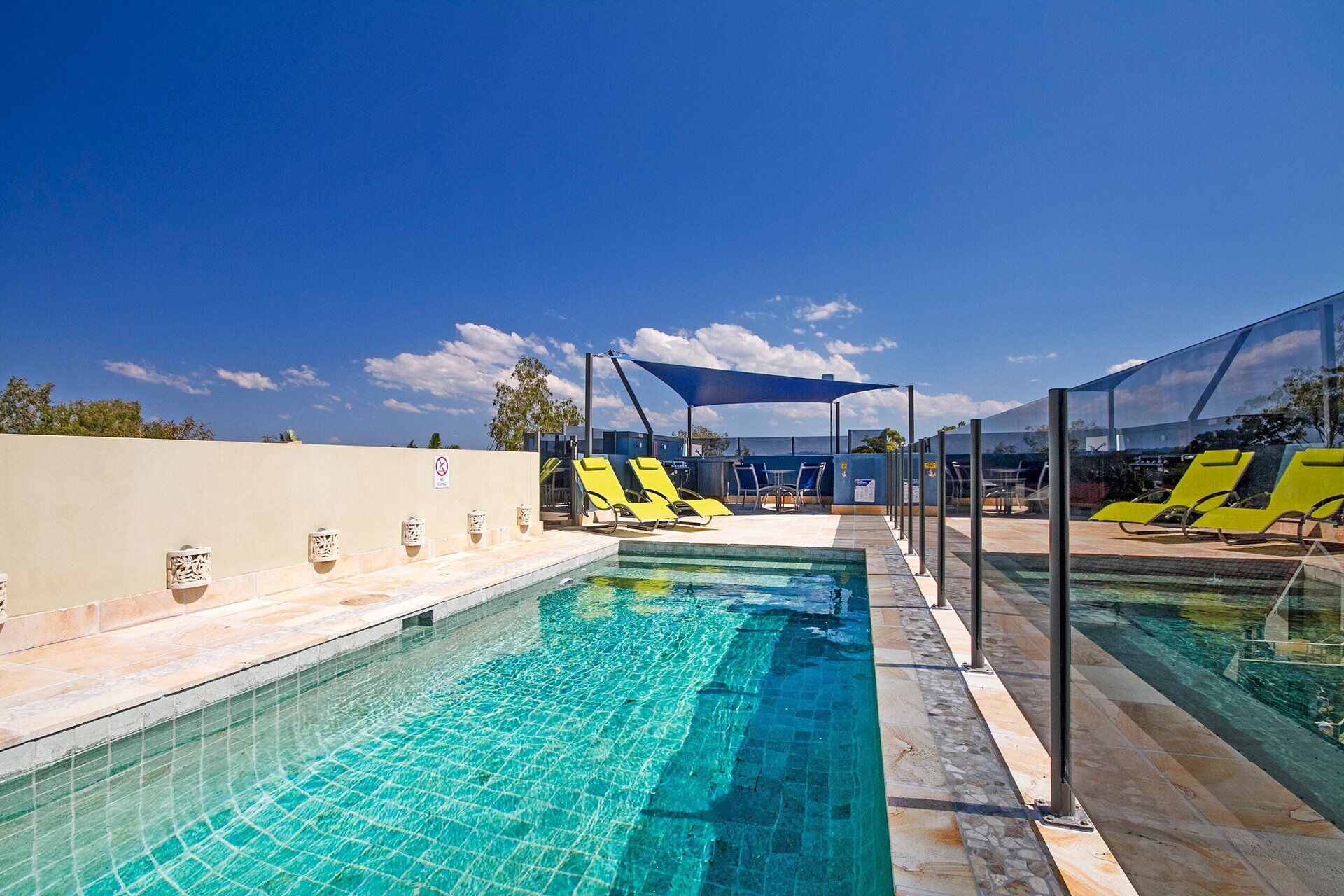 A swimming pool with sun loungers and a covered seating area.