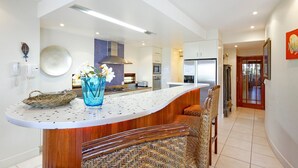 A modern kitchen with a curved island, a built-in oven, and a stainless steel refrigerator. - Noosa Dua 2 - Balinese Retreat (Noosaville)