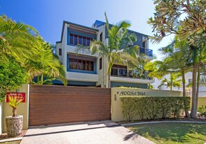A modern multi-story building with a gated entrance, surrounded by palm trees and a well-maintained lawn. - Noosa Dua 2 - Balinese Retreat (Noosaville)
