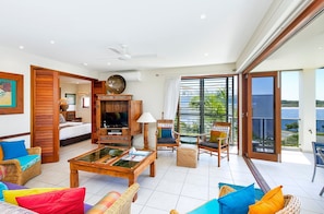 A spacious living area with a television, comfortable seating, and a view of the outdoors.