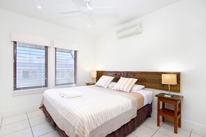 A hotel room with a bed, a nightstand, a lamp, and a ceiling fan.