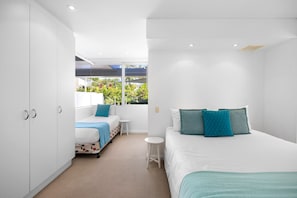 Relax in a serene space with a large bed and sofa, surrounded by a peaceful view of greenery.