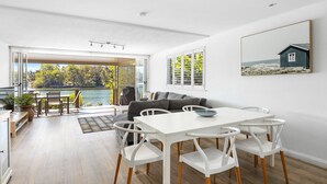 A modern interior with a dining area, a sofa, and a view of a lake. - Noosa Haven Apt 6 - Riverside Retreat (Noosaville)