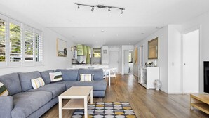 A modern living room with a grey sectional sofa, a wooden coffee table, and a patterned rug. - Noosa Haven Apt 6 - Riverside Retreat (Noosaville)