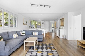 A modern living room with a grey sectional sofa, a wooden coffee table, and a patterned rug.