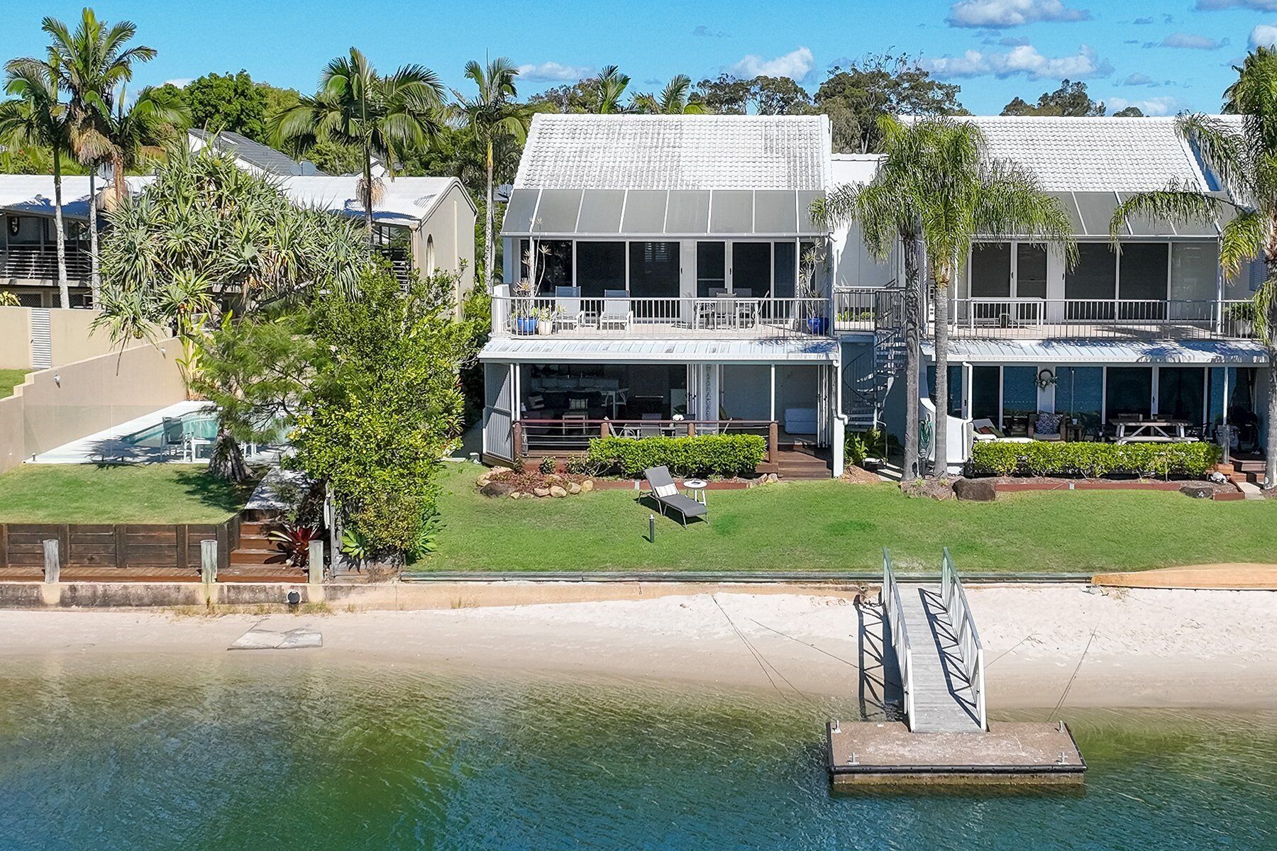 Ein zweistöckiges Haus mit Balkon, Pool und Blick auf den Strand.