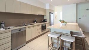 Una cocina moderna con una isla central, taburetes de bar y electrodomésticos de acero inoxidable.