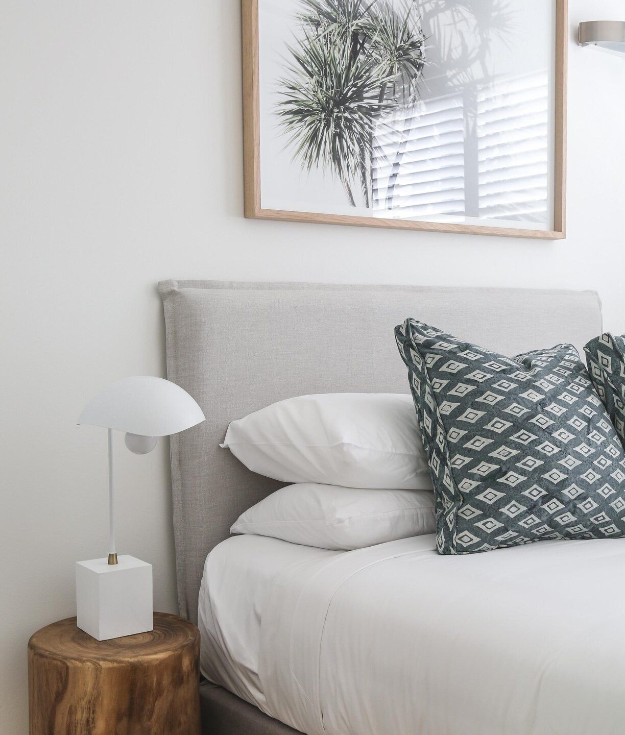 Una camera da letto con un letto, un comodino, una lampada e un quadro appeso al muro.