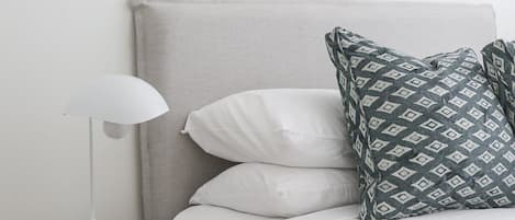 Una camera da letto con un letto, un comodino, una lampada e un quadro appeso al muro.