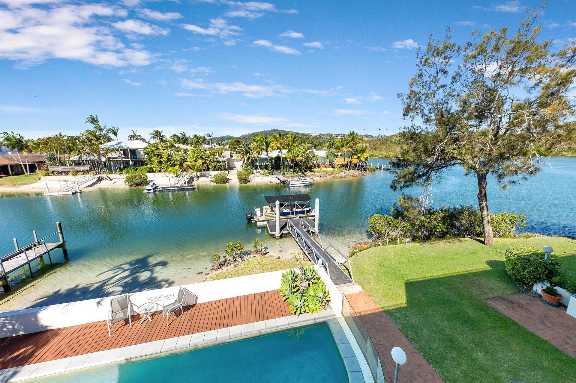 A waterfront property with a swimming pool, dock, and boats.
