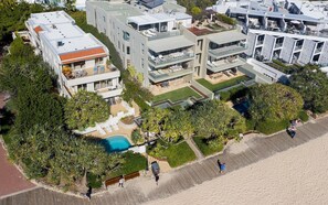 A modern residential complex with multiple balconies, a swimming pool, and lush landscaping.
