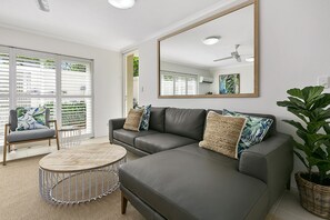 Relax in this stylish living room with a comfortable sofa, coffee table, and large mirror.
