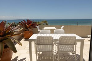 A terrace with a table and chairs, a potted plant, and a view of the sea. - Portofino 7 - Beachfront Penthouse (Noosa Heads)