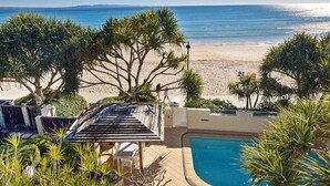 Un espace piscine offrant une vue sur la plage et l’océan.