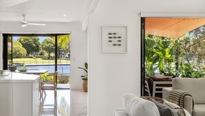A modern living room with a view of a swimming pool and garden.