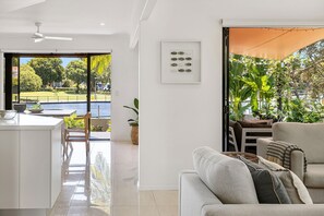 A modern living room with a view of a swimming pool and garden.