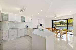 A modern kitchen with white cabinetry, a central island, and a view of a lake through large windows.