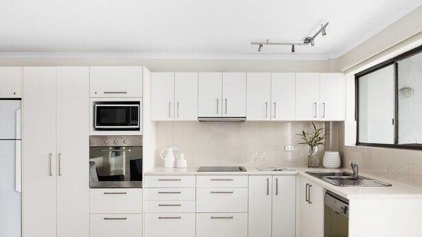 A modern kitchen with white cabinetry, stainless steel appliances, and a dishwasher. - Soundhaven 1 - Prime Location (Noosa Heads)