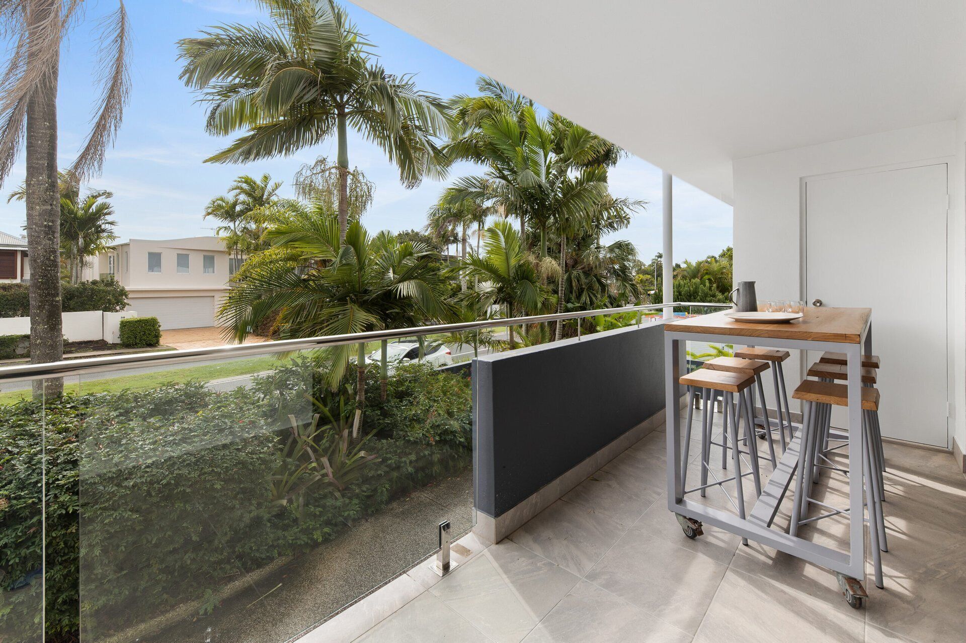 Un balcón con vistas a palmeras y una zona residencial.