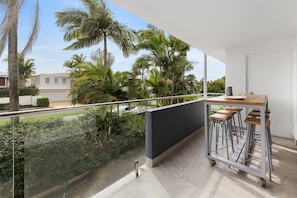 Un balcon donnant sur des palmiers et une zone résidentielle.