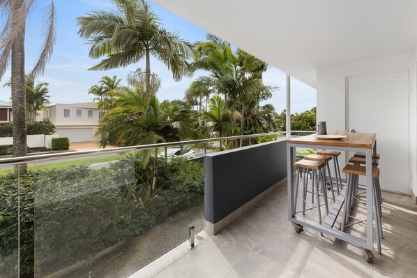 A balcony with a view of palm trees and a residential area.