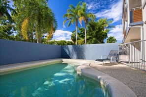 Relax by the serene pool surrounded by lush greenery and modern architecture.