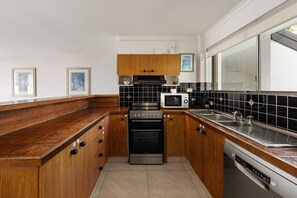 A kitchen with wooden cabinets, a microwave, a stove, and a dishwasher.
