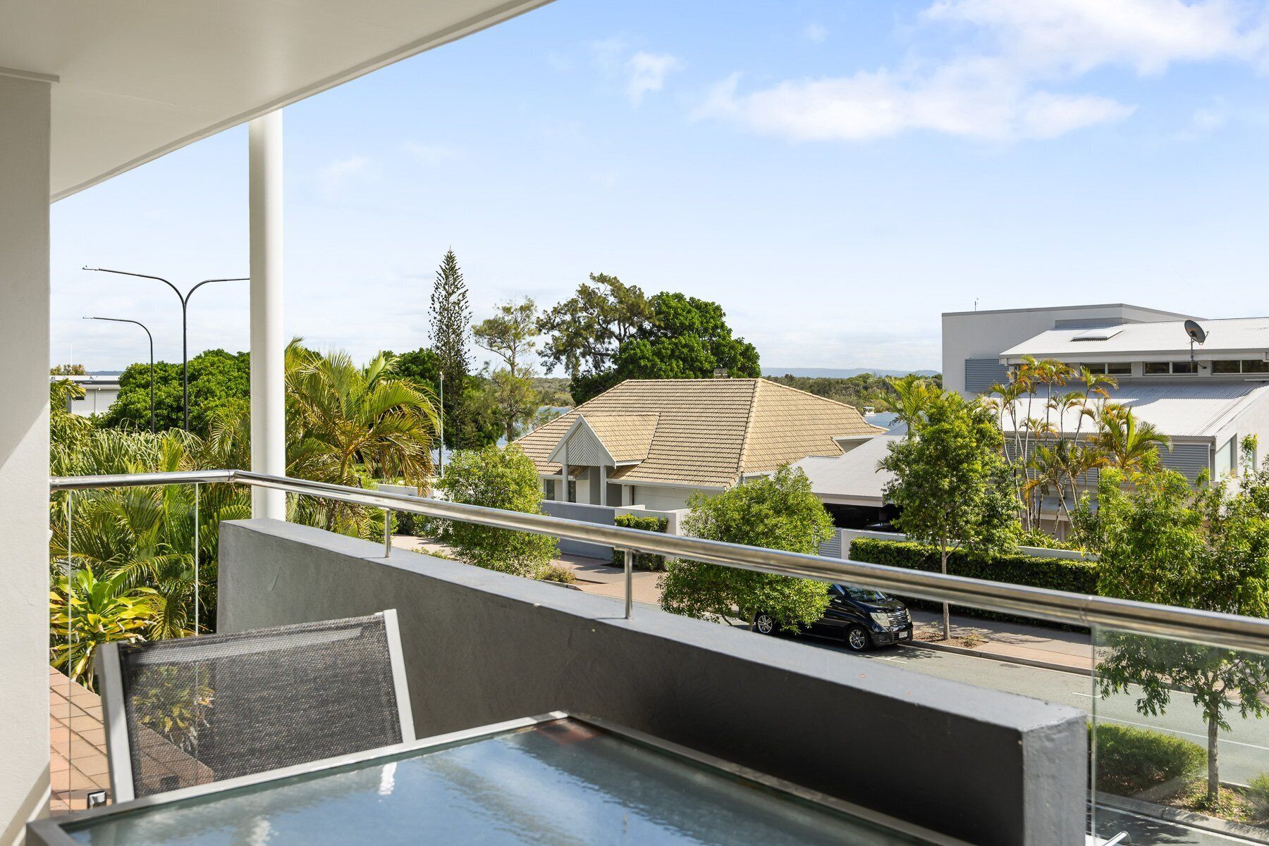 A balcony with a view of a residential area, including houses and trees.