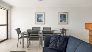 A modern living room with a sofa, a dining table with chairs, and two framed artworks on the wall. - Soundhaven 4 - Noosa Parade Value (Noosa Heads)