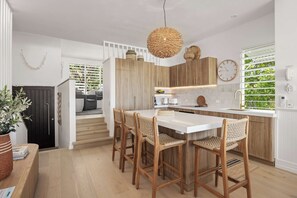 Een moderne keuken met een centraal eiland, houten stoelen en een hanglamp.