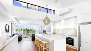 A modern kitchen with a central island, bar stools, and a view to the outdoors.