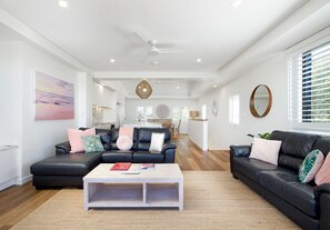 Ein modernes Wohnzimmer mit zwei schwarzen Ledersofas, einem weißen Couchtisch und einem großen Gemälde an der Wand.