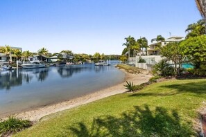 Una marina con barche, una spiaggia sabbiosa e edifici residenziali con palme.