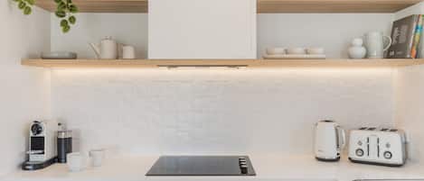 Een moderne keuken met witte kasten, een zwart inductiekookplaat, een broodrooster en een waterkoker.